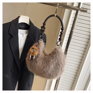 Detail of hobo faux fur shoulder bag with dark bead handle and cute plush charm