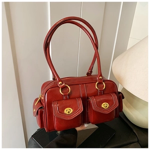 Detail of red vintage leather bag featuring dual front pockets and golden turn-lock buckles