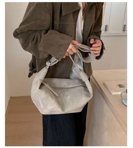 Close-up of gray suede hobo bag with unique knotted strap and sleek zipper detail