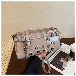 Detail of glossy nude patent leather handbag with silver eyelets and metal buckle straps