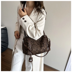 Detail of leopard print faux fur tote bag with brown leather strap and metal lock charm