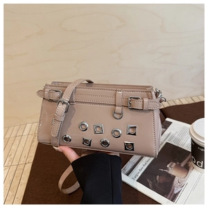 Detail of beige patent leather small square bag with metal eyelets and adjustable strap