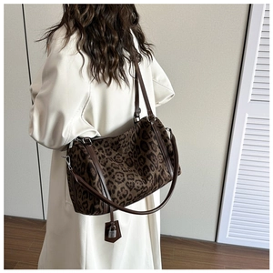 Detail view of large leopard print tote bag with brown leather straps and a metal lock charm