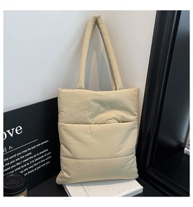 Close-up detail of soft quilted puffer tote bag in beige with long shoulder straps