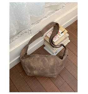 Detail of vintage brown crescent bag with wide strap and distressed leather texture