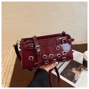 Detail of burgundy patent leather bag with silver eyelets and buckle decoration