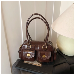 Detail of vintage dark brown Boston bag with glossy texture and gold metal turn-locks