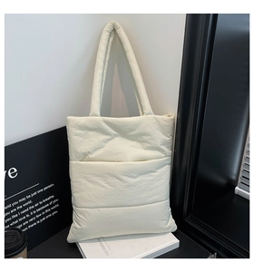 Detailed view of white quilted puffer tote bag with thick shoulder straps and soft texture