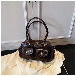 Detail of dark brown retro shoulder bag with twin front pockets and gold turn-locks