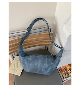 Detail of blue faux suede slouchy hobo bag with adjustable wide shoulder strap and metal buckle