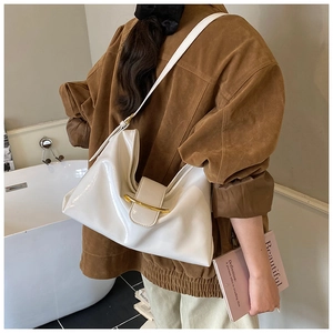 Détail du sac Hobo blanc brillant avec fermoir doré porté à l'épaule par un mannequin