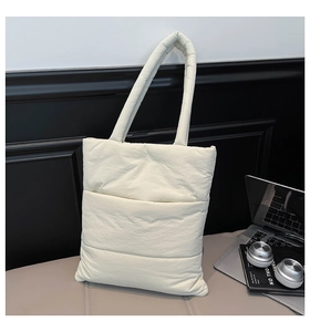 Detailed quilted texture of off-white padded tote bag in a modern office setup