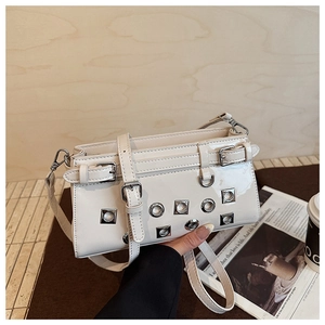 Chic beige patent leather handbag featuring silver punk eyelets and buckled straps detail