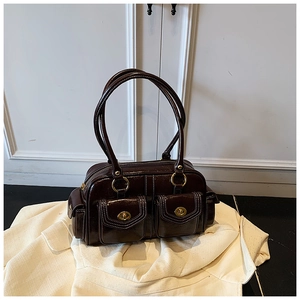 Detail of dark brown vintage boston bag with gold twist locks and oil wax leather texture