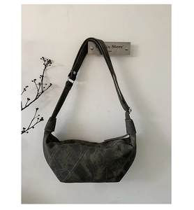 Detail of dark grey suede crescent bag with diagonal stitching and adjustable strap