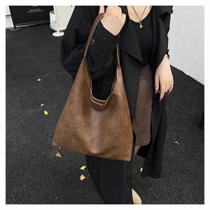 Detail of a large brown vintage leather hobo bag with textured grain in autumn street scene