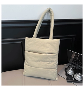 Detailed macro view of quilted puffer tote bag in oat beige with visible zipper pocket
