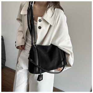 Minimalist black matte faux suede tote bag featured on a model wearing a white coat