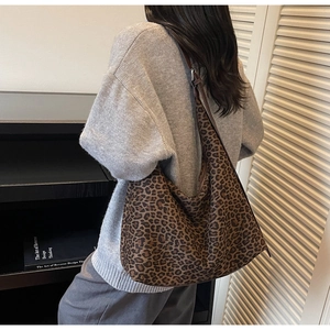 Detail showing the slouchy drape and texture of the leopard print tote bag on a shoulder