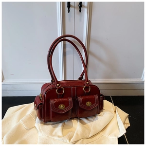 Detailed view of dark red vintage leather handbag with front pockets and golden buckles