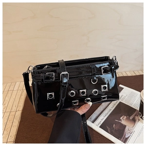Detail of black patent leather shoulder bag with industrial metallic eyelets and studs