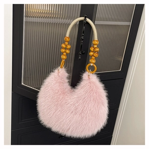 Close-up of pink faux fur shoulder bag featuring braided strap with wooden bead accents