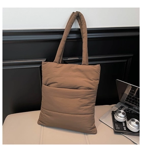 Detail of the brown quilted puffer tote bag with padded strap in a modern minimalist style