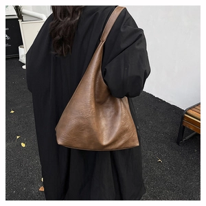 Macro detail of the smooth caramel brown leather texture on a spacious hobo tote bag