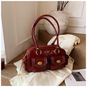 Close-up of shiny dark red leather boston bag with golden twist-lock front pockets