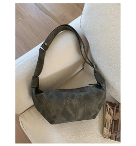 Detail of grey suede croissant bag featuring stitched panels and adjustable shoulder strap