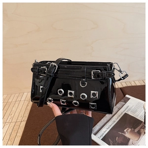 Detail of glossy black patent leather crossbody bag with silver eyelet studs and hardware