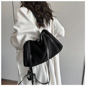 Minimalist black oversized shoulder bag with silver lock charm on a model side view