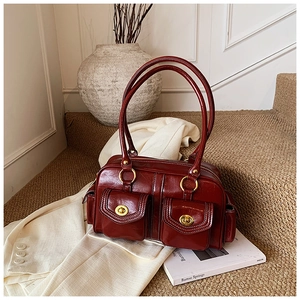 Detail of red-brown oil wax leather Boston bag with vintage gold metal buckles and pockets