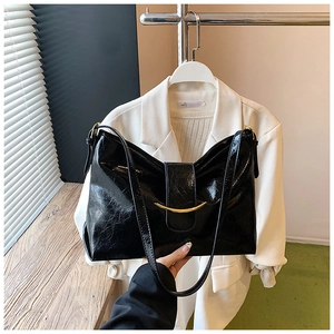 Détail du sac cabas en cuir noir brillant avec un fermoir doré en forme de croissant