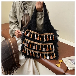 Gros plan détaillé d'un sac cabas bohème en peluche noire avec pompons colorés et texture