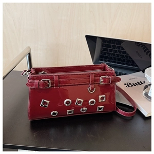Detail view of red patent leather crossbody bag featuring hollow silver metal rivets