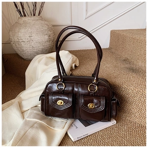 Macro detail of dark brown retro pillow bag with glossy pleated leather and golden locks