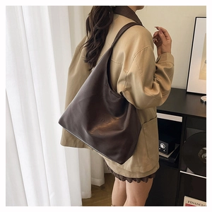 Detail view of the soft brown leather texture and relaxed silhouette of a large tote bag