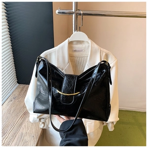Détail d'un sac cabas en cuir ciré noir avec garniture dorée et texture plissée chic
