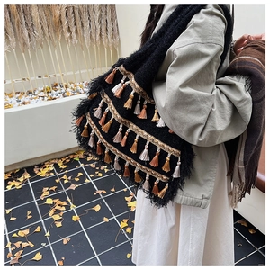 Détail d'un sac cabas bohème avec pompons ethniques et finitions de rubans tressés