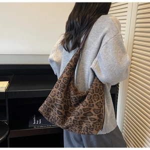Detail of a large leopard print shoulder bag worn by a model in a minimalist setting