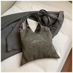 Detail of dark grey tote bag featuring U-shaped opening and gothic metal hardware accents