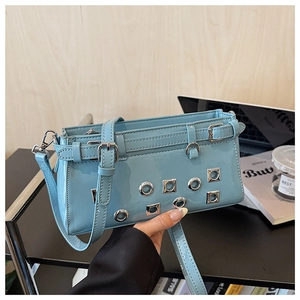 Detail of light blue punk messenger bag with rivets and decorative straps in lifestyle setting