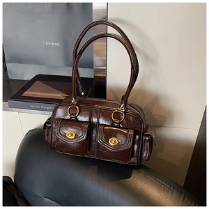 Macro detail of dark brown oil wax leather pillow bag with gold twist-lock pockets