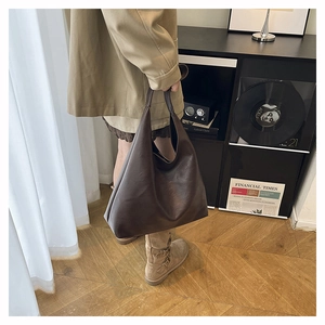 Minimalist large brown hobo tote bag in matte leather shown in a stylish lifestyle setting