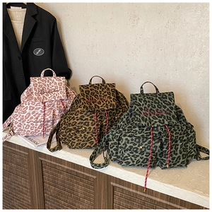 Detailed close-up of leopard canvas backpacks in pink, brown and green with rope drawstring