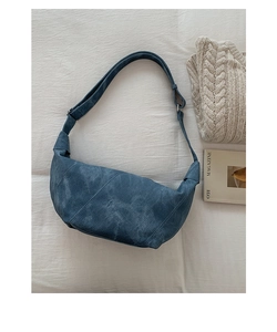 Flat lay of vintage dark blue crescent bag with geometric stitching on linen background