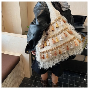 Détail du sac cabas bohème en tricot avec rayures dorées et pompons à franges colorés