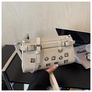 Detail of cream white punk style shoulder bag with metallic eyelets and buckle accents