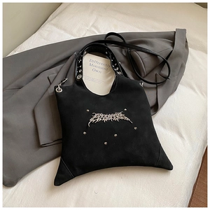 Detail view of black matte irregular tote bag with silver gothic hardware and studs